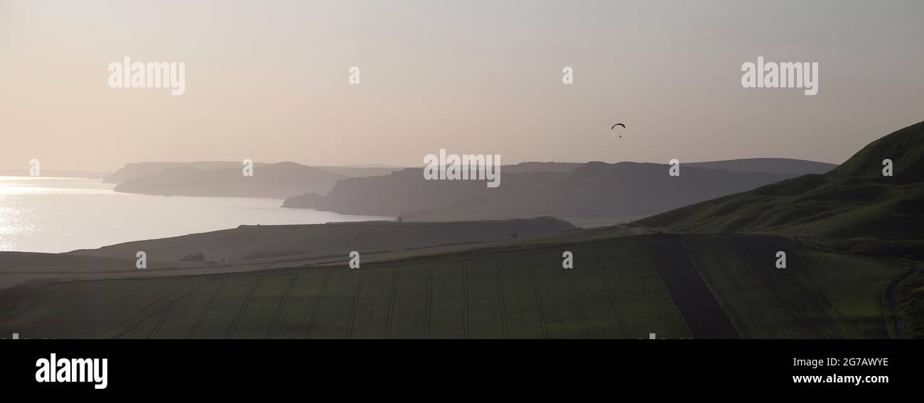 Paragliding over the green fields and coast of Dorset, near Corfe castle - England. Stock Photo