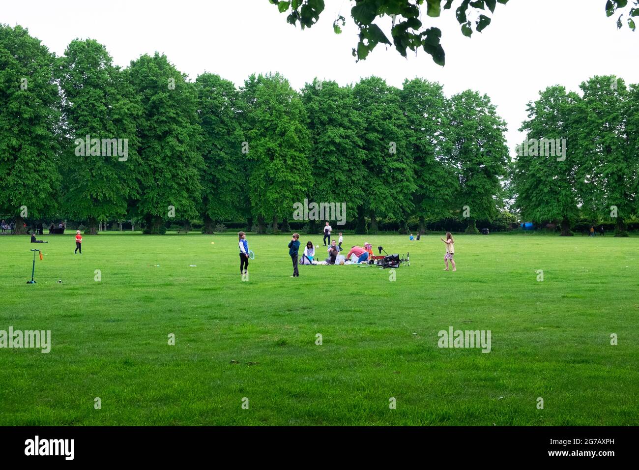 A family sitting on blanket in St James Park Walthamstow during the covid 19 pandemic in spring 2021 Walthamstow East London Englan UK KATHY DEWITT Stock Photo