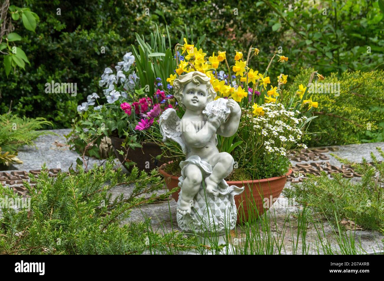 Germany, Baden-Wuerttemberg, Blaustein-Lautern, flower bowl with spring flowers, angel sculpture in the churchyard of the Protestant Church of Our Lady Stock Photo