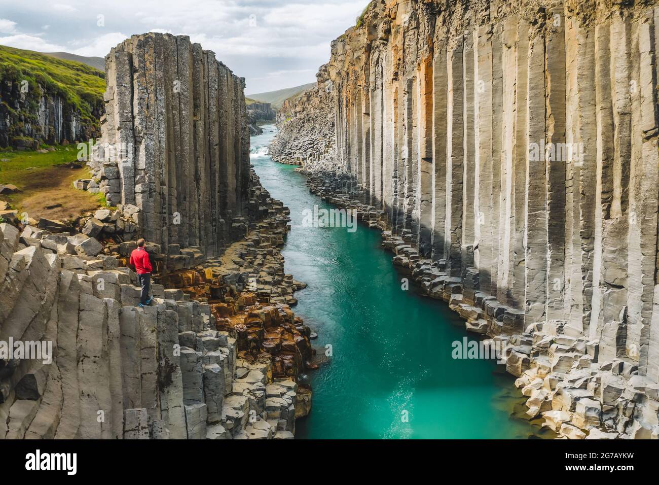 Man hiker in red jacket visit Studlagil basalt canyon, with rare volcanic basalt column formations, Iceland. Stock Photo