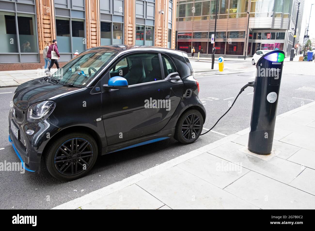 Black Smart ForFour small electric car recharging at charging station on a street in the City of London UK  KATHY DEWITT Stock Photo