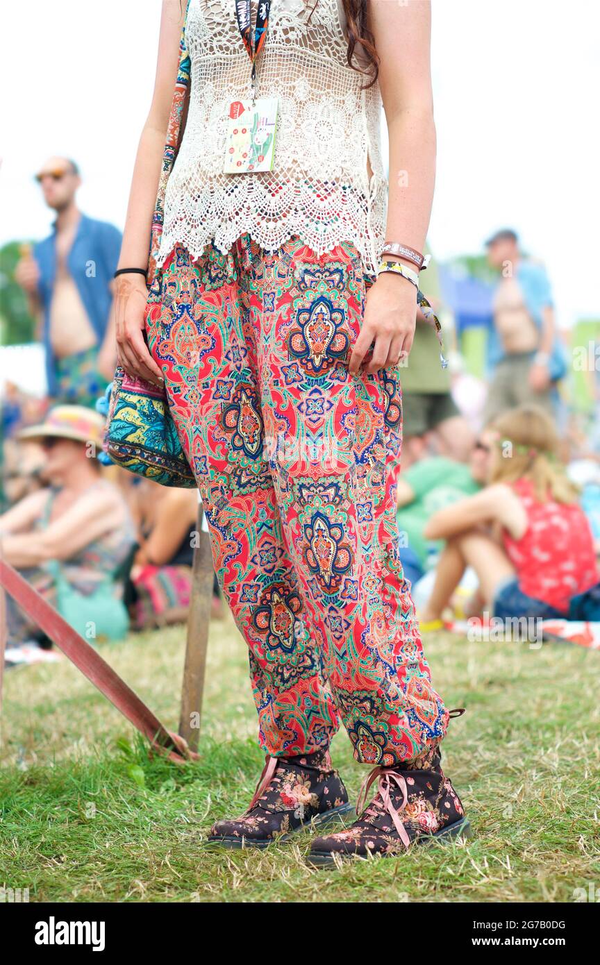Young woman wearingn colourful trousers and Dr Marten boots with floral design. Womad festival, England Stock Photo