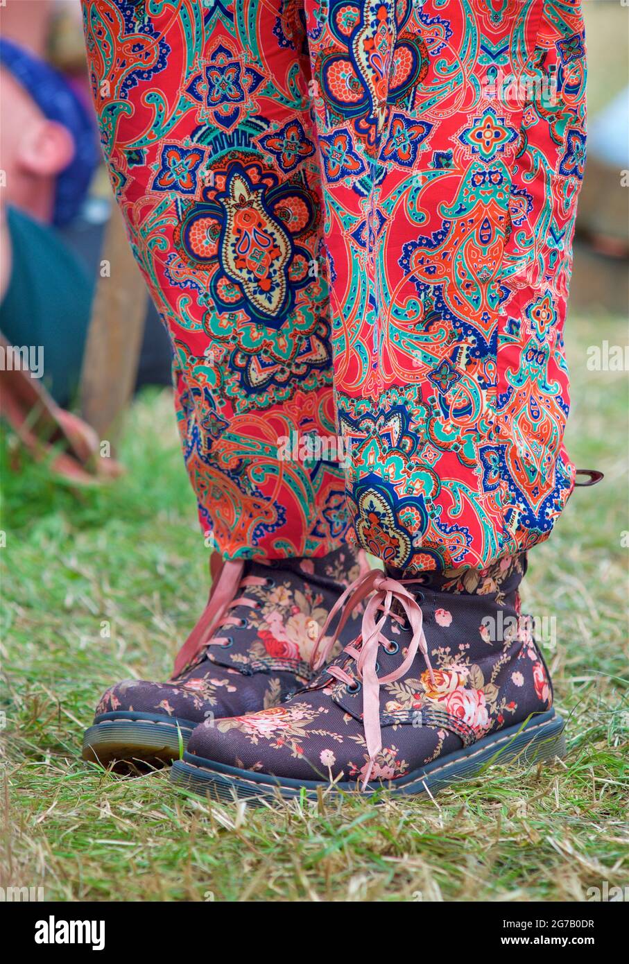 Young woman wearingn colourful trousers and Dr Marten boots with floral design. Womad festival, England Stock Photo