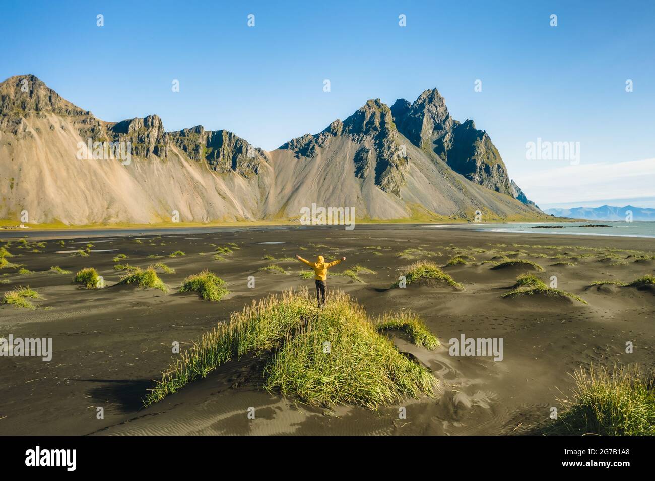 Iceland. Aerial view of man hiker with backpack at black sand dunes on the Stokksnes headland on southeastern Icelandic coast with Vestrahorn. Europe. Stock Photo