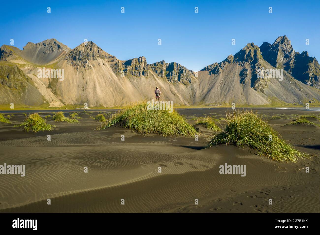 Iceland. Aerial view of woman hiker with backpack at black sand dunes on the Stokksnes headland on southeastern Icelandic coast with Vestrahorn. Europe. Stock Photo