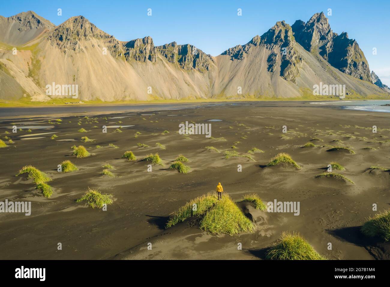 Iceland. Aerial view of man hiker with backpack at black sand dunes on the Stokksnes headland on southeastern Icelandic coast with Vestrahorn. Europe. Stock Photo