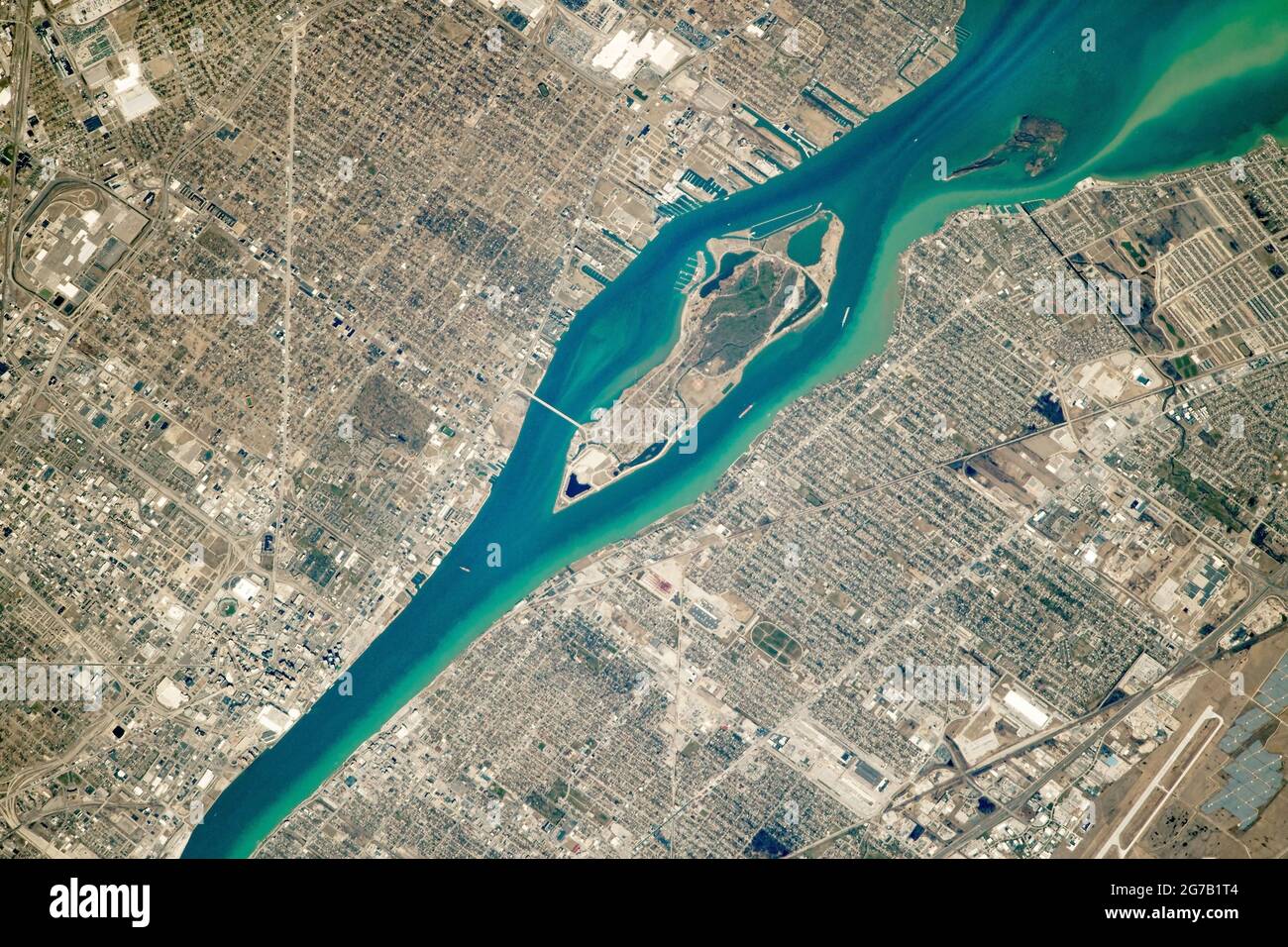 Photographed from the International Space Station (ISS). Belle Isle, an island in the Detroit River, Michigan, USA. The Detroit River stretches approximately 45 kilometers (30 miles) and provides connectivity between the upper Great Lakes and the Saint Lawrence Seaway. In the photo, a few large ships are visible passing along the narrow strait. The river serves as the international border between the United States and Canada. On the U.S. side of the river lies Michigan's most populous city, Detroit. An optimised and digitally enhanced version of an NASA image / credit NASA Stock Photo