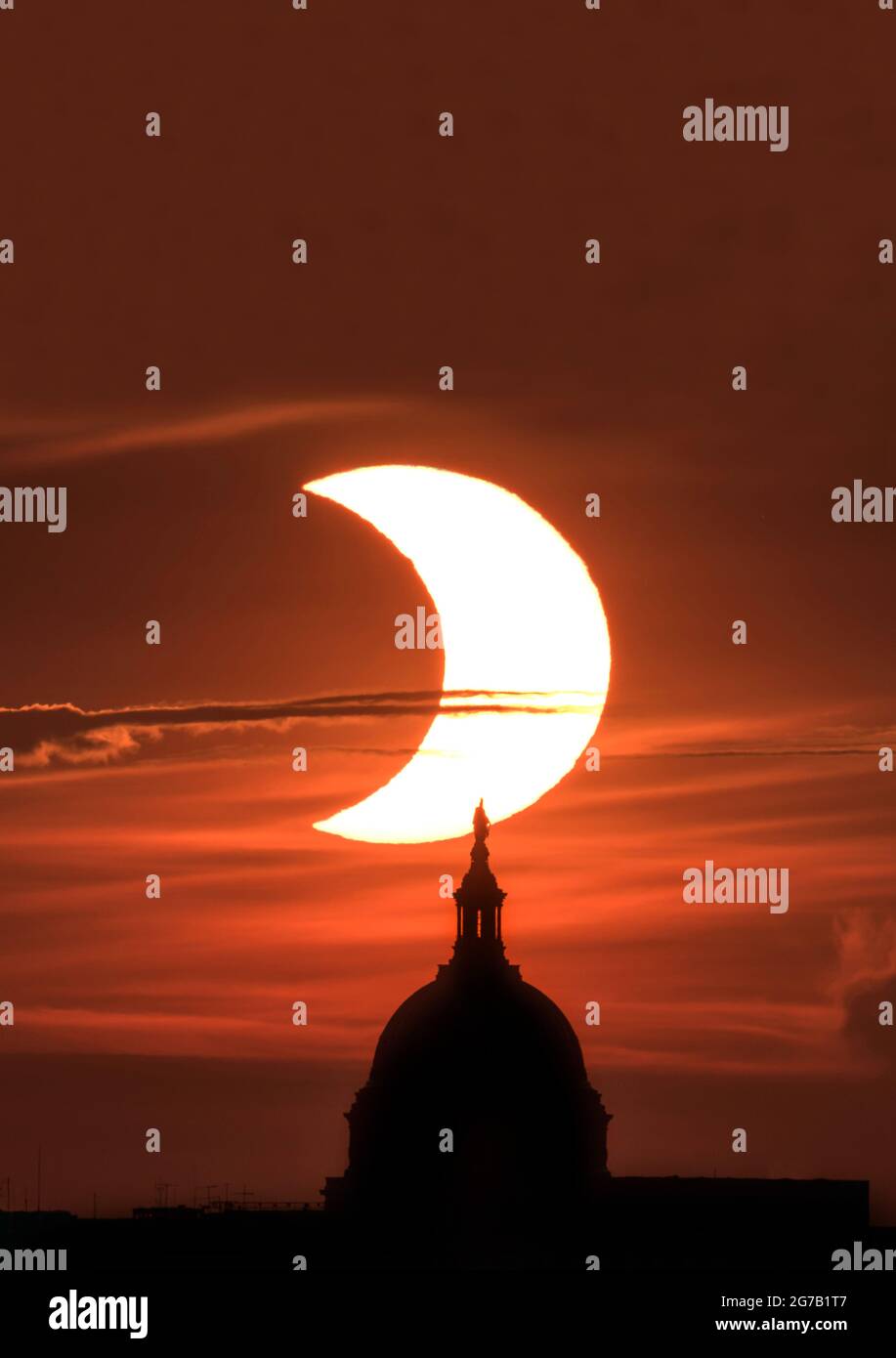 The partial solar eclipse of 10 June 2021 is seen rising above the US Capitol building in Washington DC, as seen from Arlington, Virginia, USA  A unique, optimised and digitally enhanced version of an NASA image by senior NASA photographer Bill Ingalis / credit NASA Stock Photo