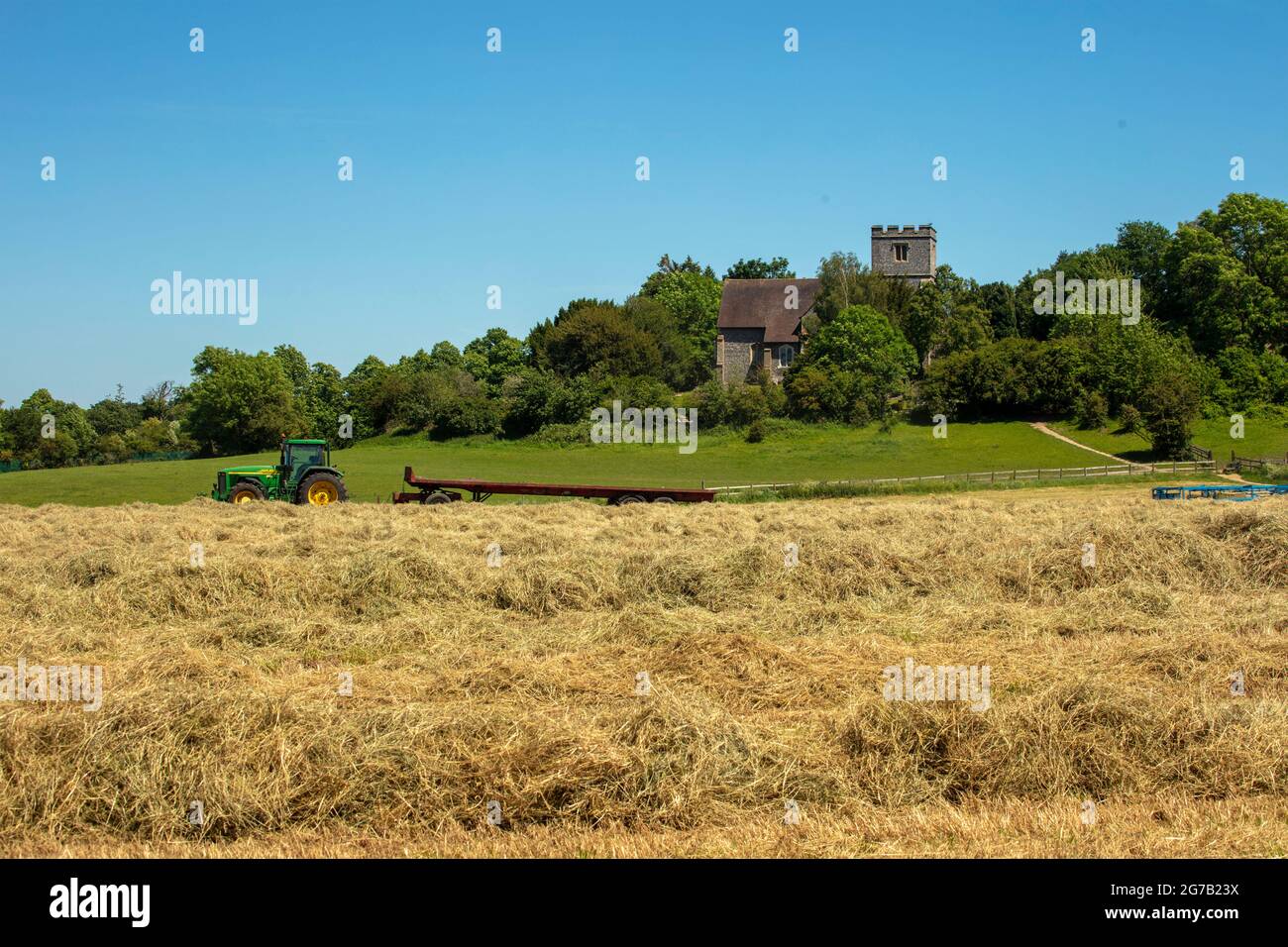 Haymaking with machines in a semi-urban farm, bright sunshine, blue sky ...