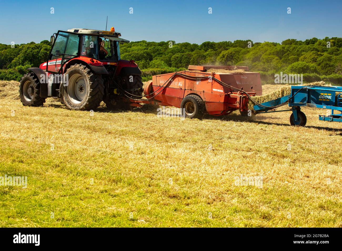 Haymaking with machines in a semi-urban farm, bright sunshine, blue sky ...