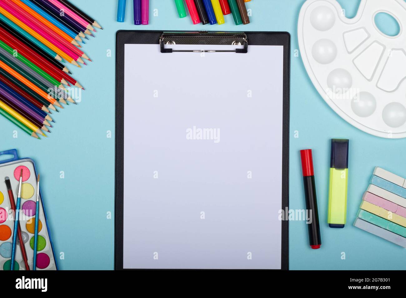 Art supplies for school painting and a blank sheet of paper on a