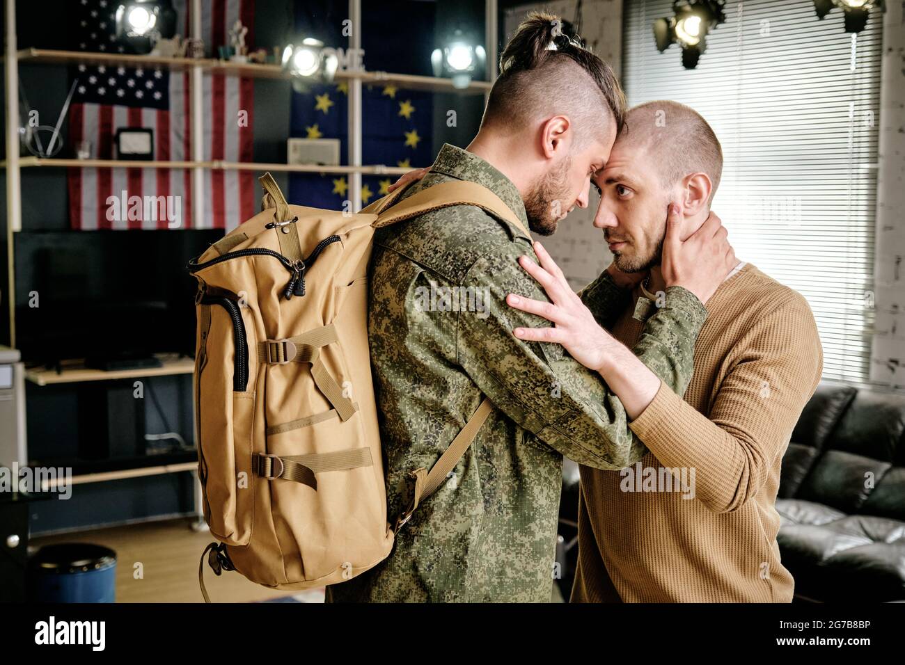 Military man in uniform hugging his boyfriend and promising to come back after military exercises Stock Photo