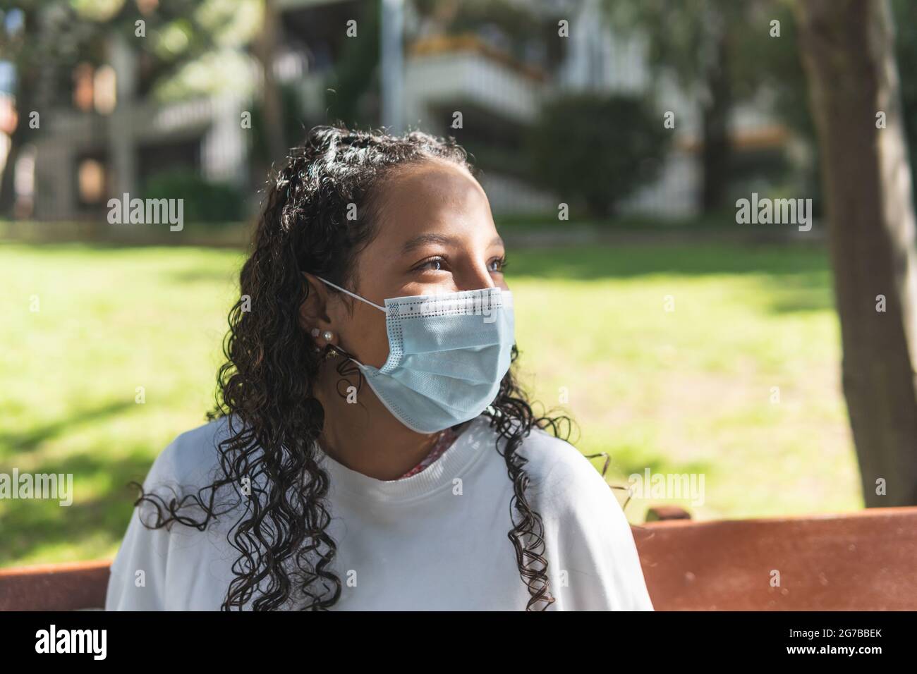 portrait of a teenage girl with a mask looking cheerfully aside on a sunny morning in a park Stock Photo