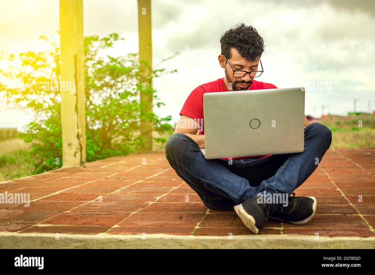 Junger Mann mit Brille arbeitet an seinem Laptop, Mann auf dem Boden mit seinem Computer El Crucero, Nicaragua Stock Photo