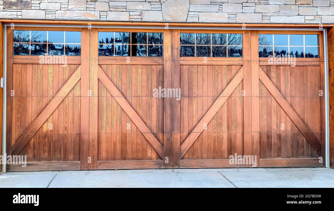 Pano Wide brown wood door with glass panes of attached garage of stone  brick home Stock Photo - Alamy