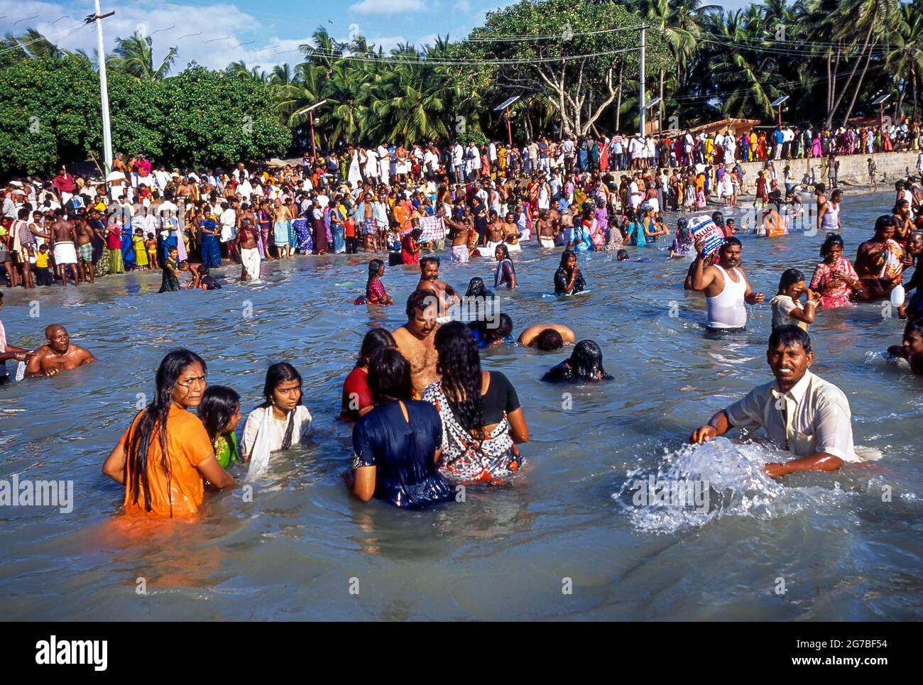 Devotees taking a dip in the holy waters of the Agni Theertham on new moon day; Aadi Amavasya day in Rameswaram, Tamil Nadu, India Stock Photo