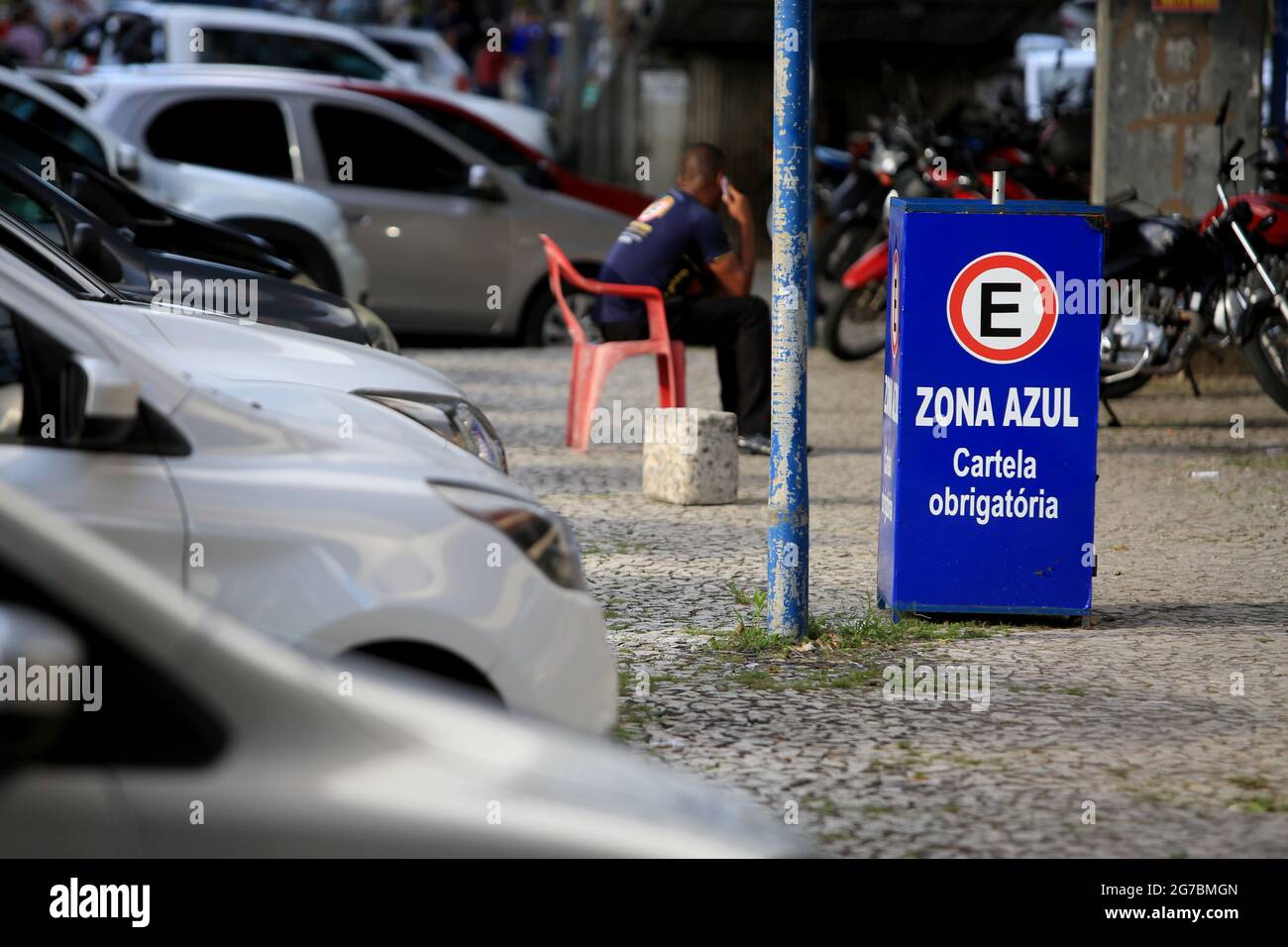 salvador, bahia, brazil - august 22, 2017: Car keeper works facing charging for parking in a zona azul location in the city of Salvador. *** Local Cap Stock Photo