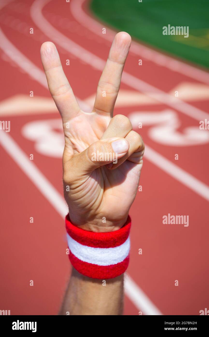 Japanese athlete with red and white wrist sweatband making a v-sign for victory with hand at a running track Stock Photo