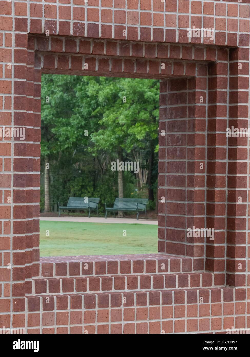 Town Green Park in The Woodlands, Texas, seen through a red brick window opening. Stock Photo