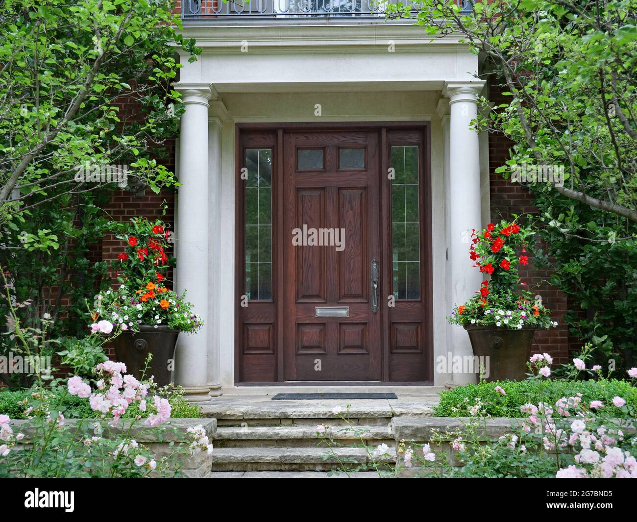 Elegant wooden front door of house with columns and flower garden Stock ...