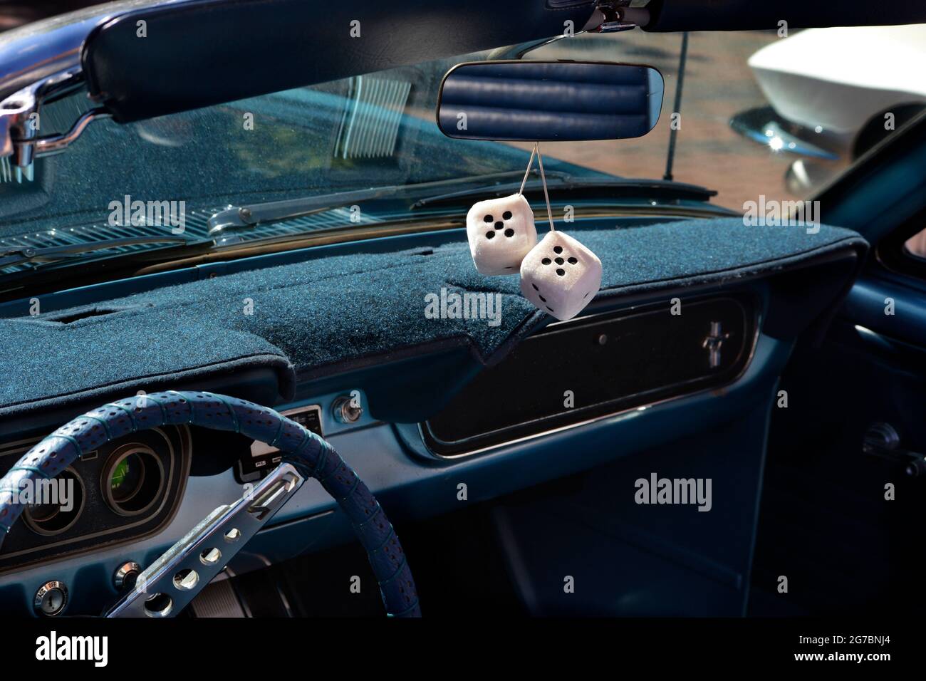 A pair of decorative fuzzy dice handing from the rearview mirror of a