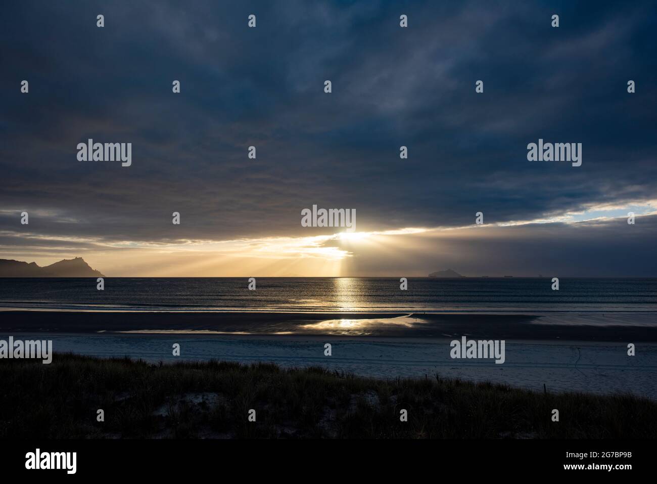 Sun shines through clouds over sea Stock Photo