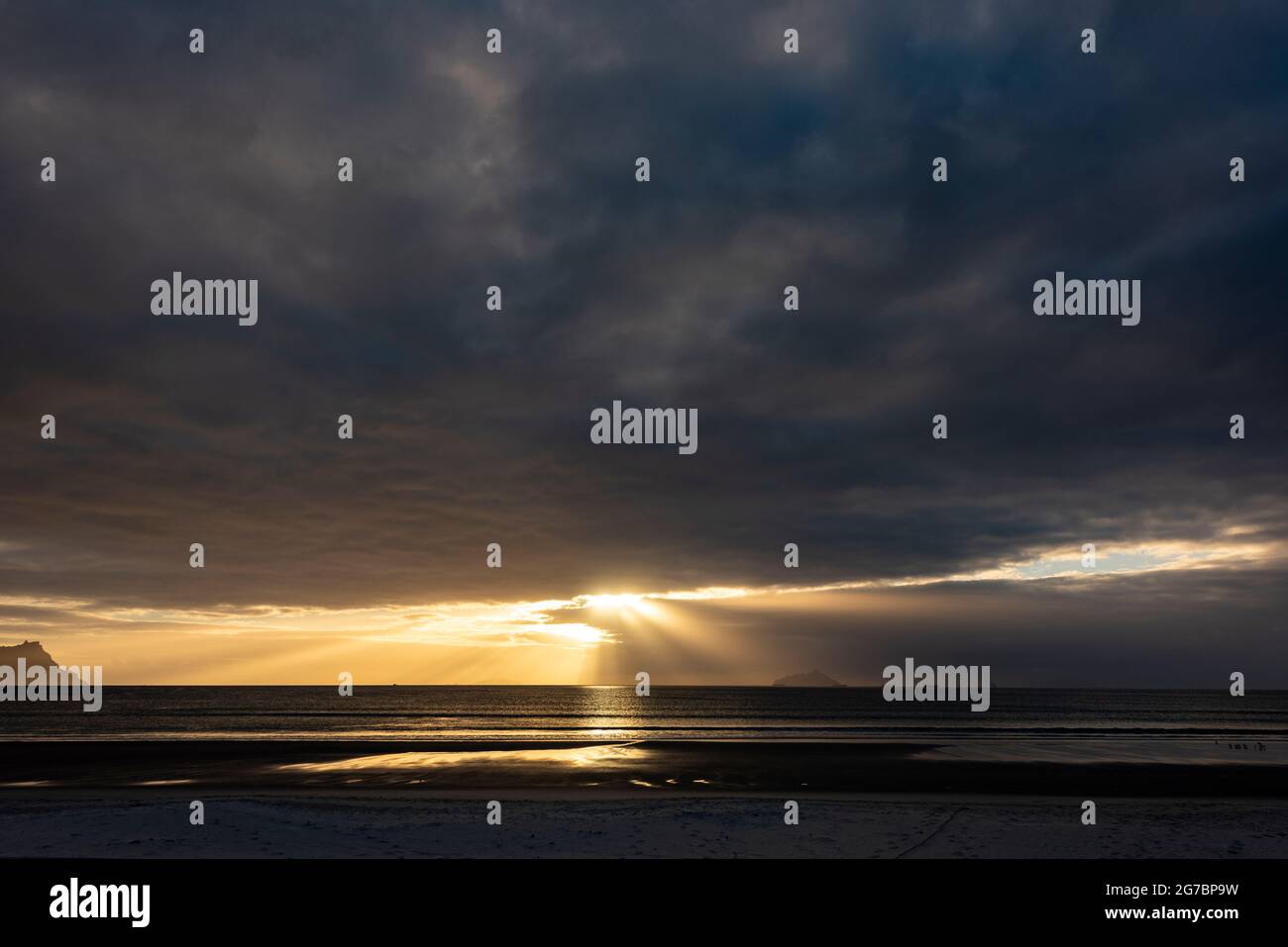 Sun shines through clouds over sea Stock Photo
