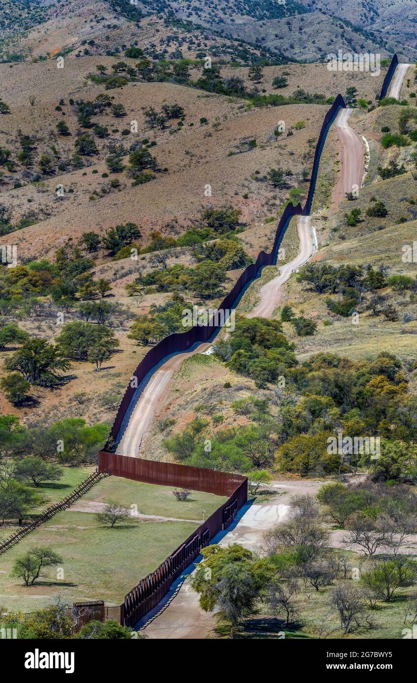 Image shows US border fence on the Mexico border, west of Nogales Arizona and Nogales Sonora Mexico, viewed from US Side, looking west. Stock Photo