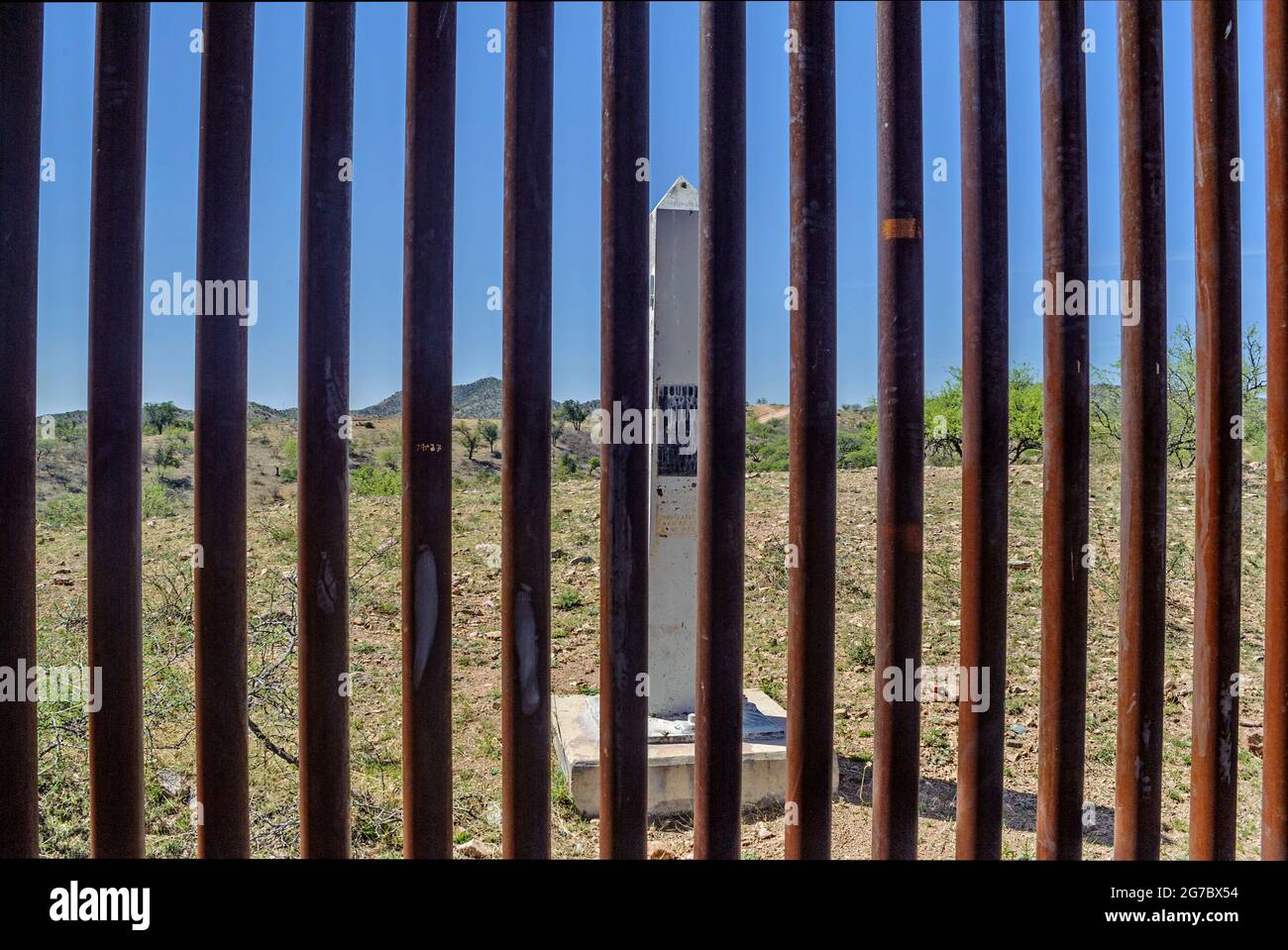 Image shows US border fence and white historic boundary monument on the Mexico border, west of Nogales Arizona and Nogales Sonora Mexico . This type o Stock Photo