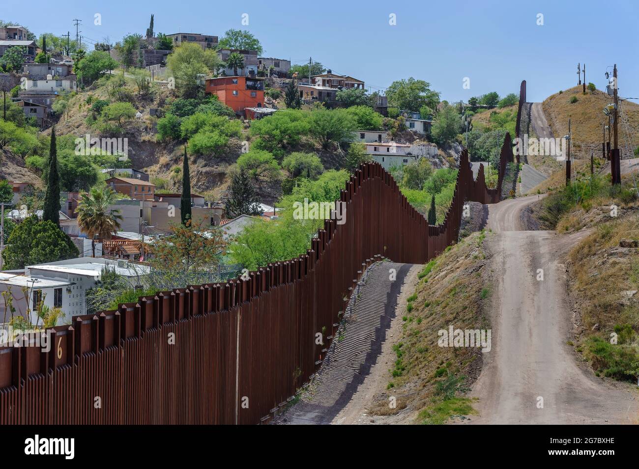 US Border fence, bollard style pedestrian barrier made of 6”x6” steel tubing, separating Nogales Arizona USA from Nogales Sonora Mexico, viewed from t Stock Photo