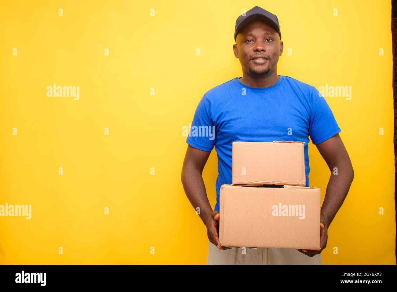 An African delivery or dispatch man carrying boxes and wearing a face cap Stock Photo