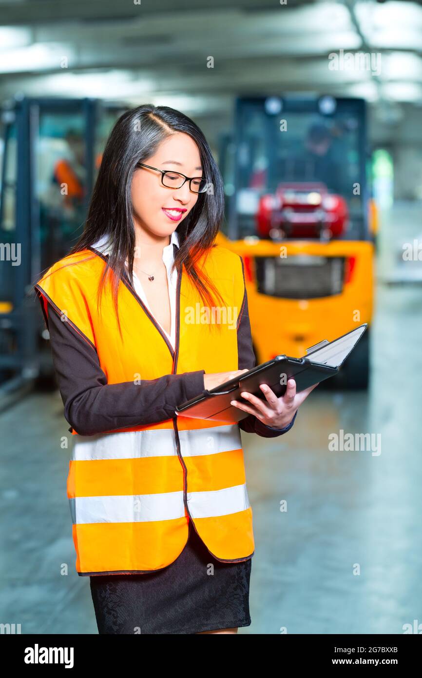 Logistics - female worker or supervisor using tablet computer at warehouse of freight forwarding company Stock Photo