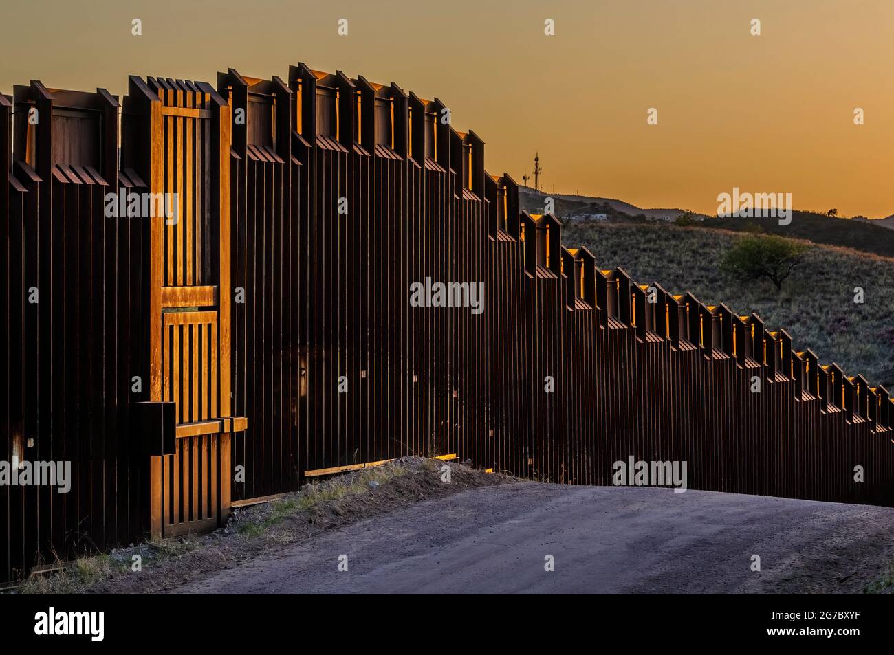 Image shows US border fence on the Mexico border, east of Nogales Arizona and Nogales Sonora Mexico, viewed from US side looking souhwest.This type of Stock Photo