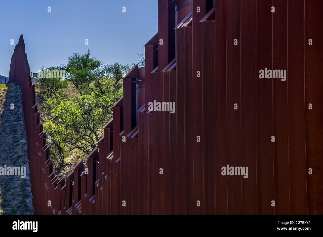 Image shows US border fence on the Mexico border, east of Nogales Arizona and Nogales Sonora Mexico, viewed from US side looking east. Note how fence Stock Photo