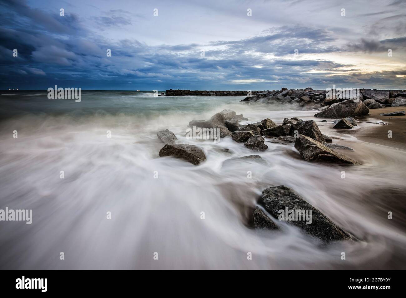 beautiful twilight colorful vivd blue and oranges graduated sky and sea behind silhouette  rocky shore with coconut trees and stone photograph with ga Stock Photo