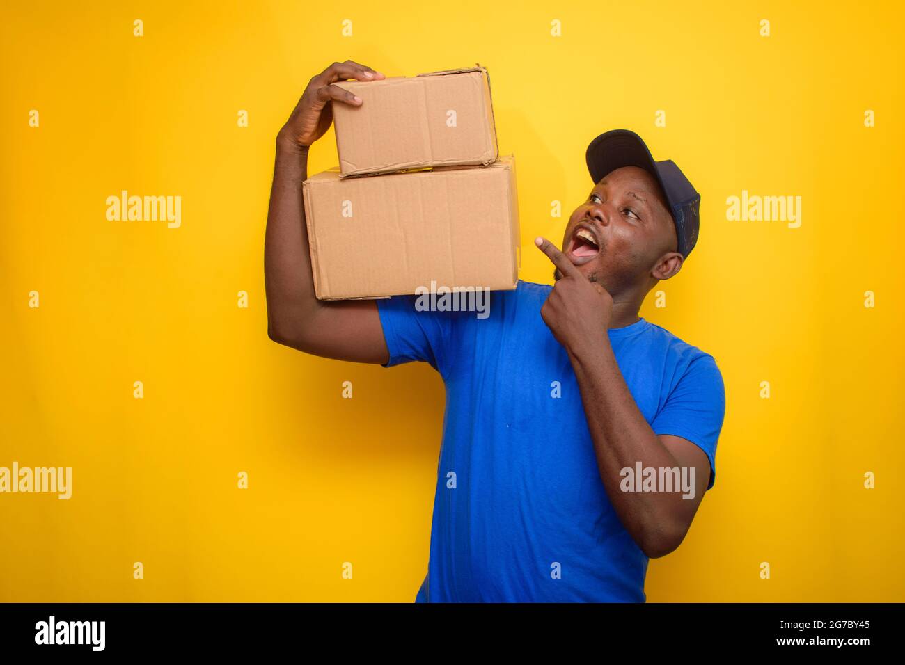 An African dispatch man with face cap, pointing to the boxes he is carrying on his shoulder Stock Photo