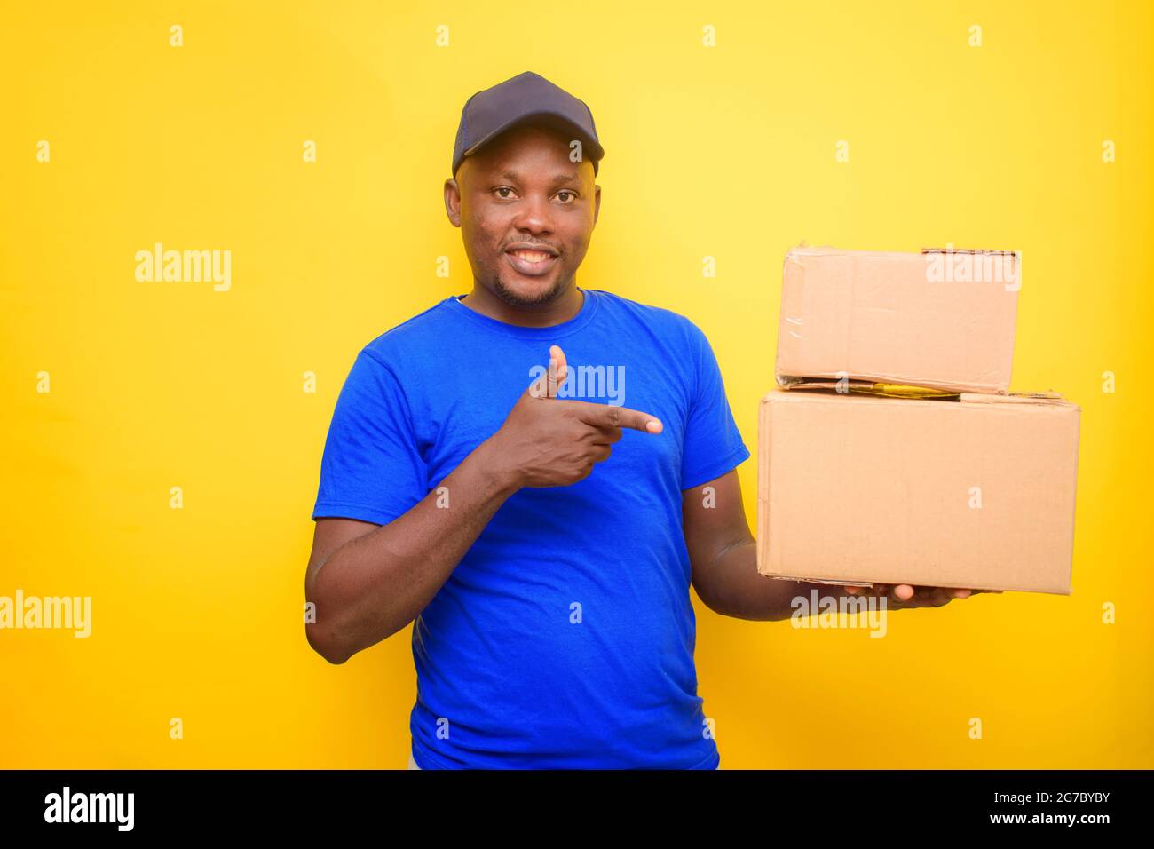 An African dispatch man with face cap and pointing to the boxes he is carrying on his shoulder Stock Photo