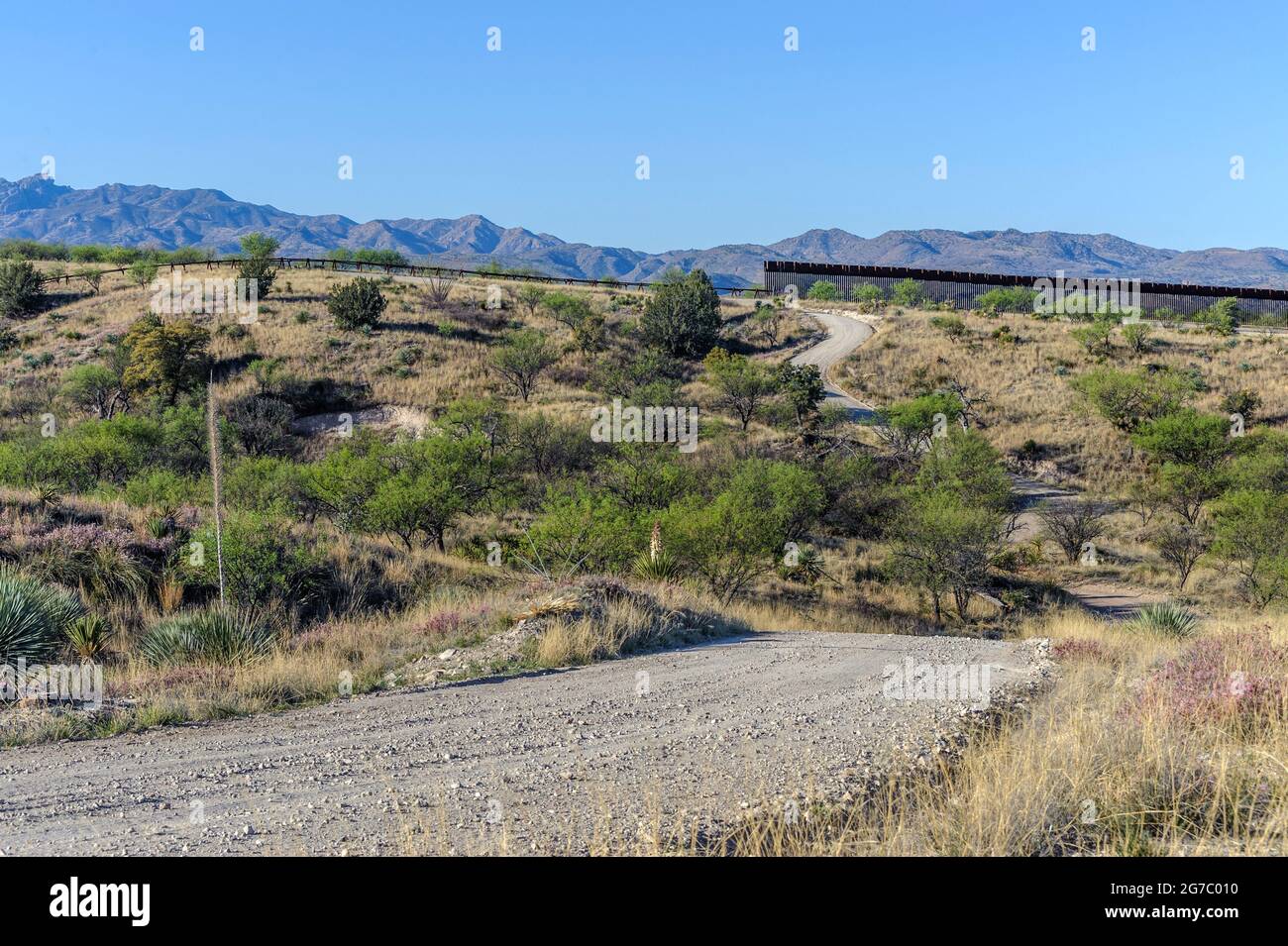 US border fence on the Mexico border, east of Nogales Arizona and Nogales Sonora Mexico, viewed from US side looking due south. On the right is tall “ Stock Photo
