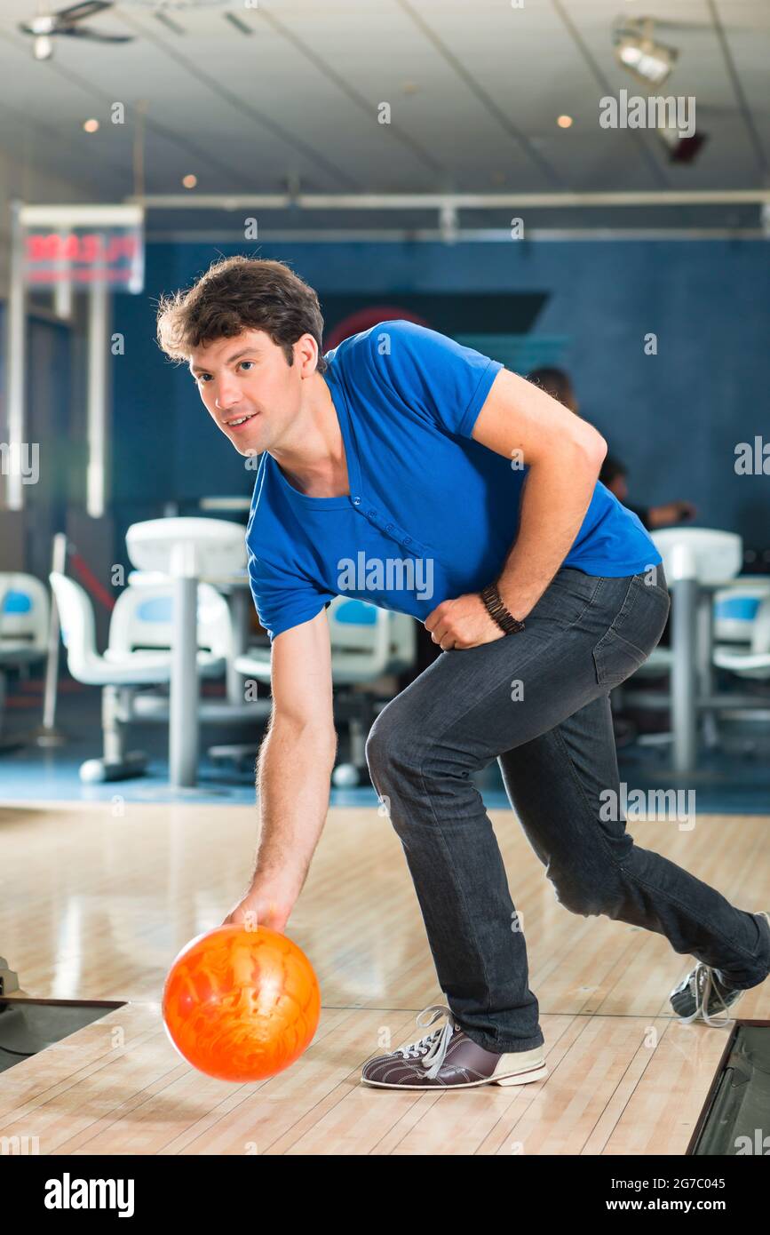 Young man in bowling alley having fun, the sporty man playing a bowling ball in front of the tenpin alley Stock Photo