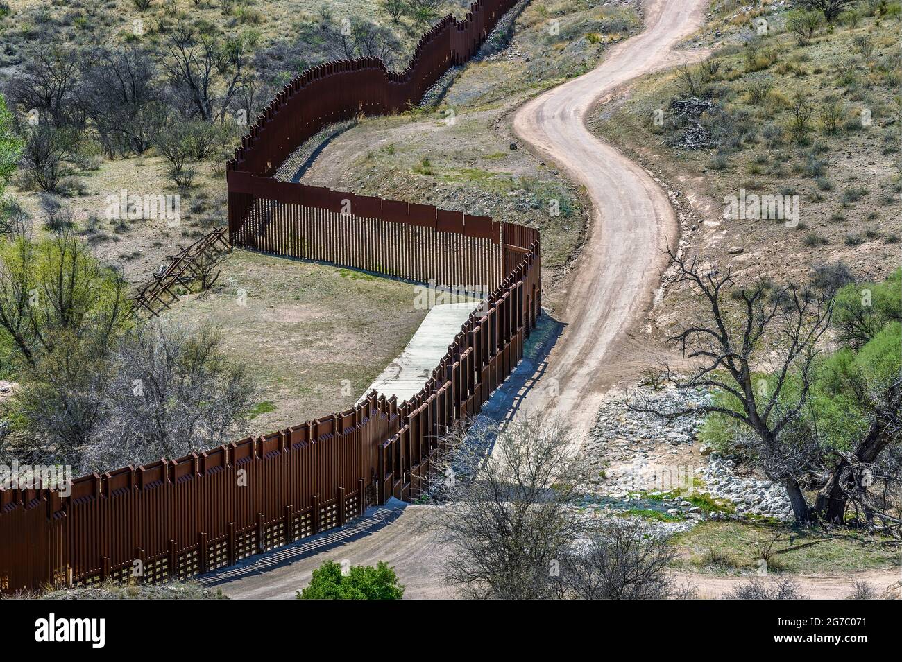 US border fence on the Mexico border, east of Nogales Arizona USA, and Nogales Sonora Mexico, viewed from US side. This type of barrier is “bollard” s Stock Photo