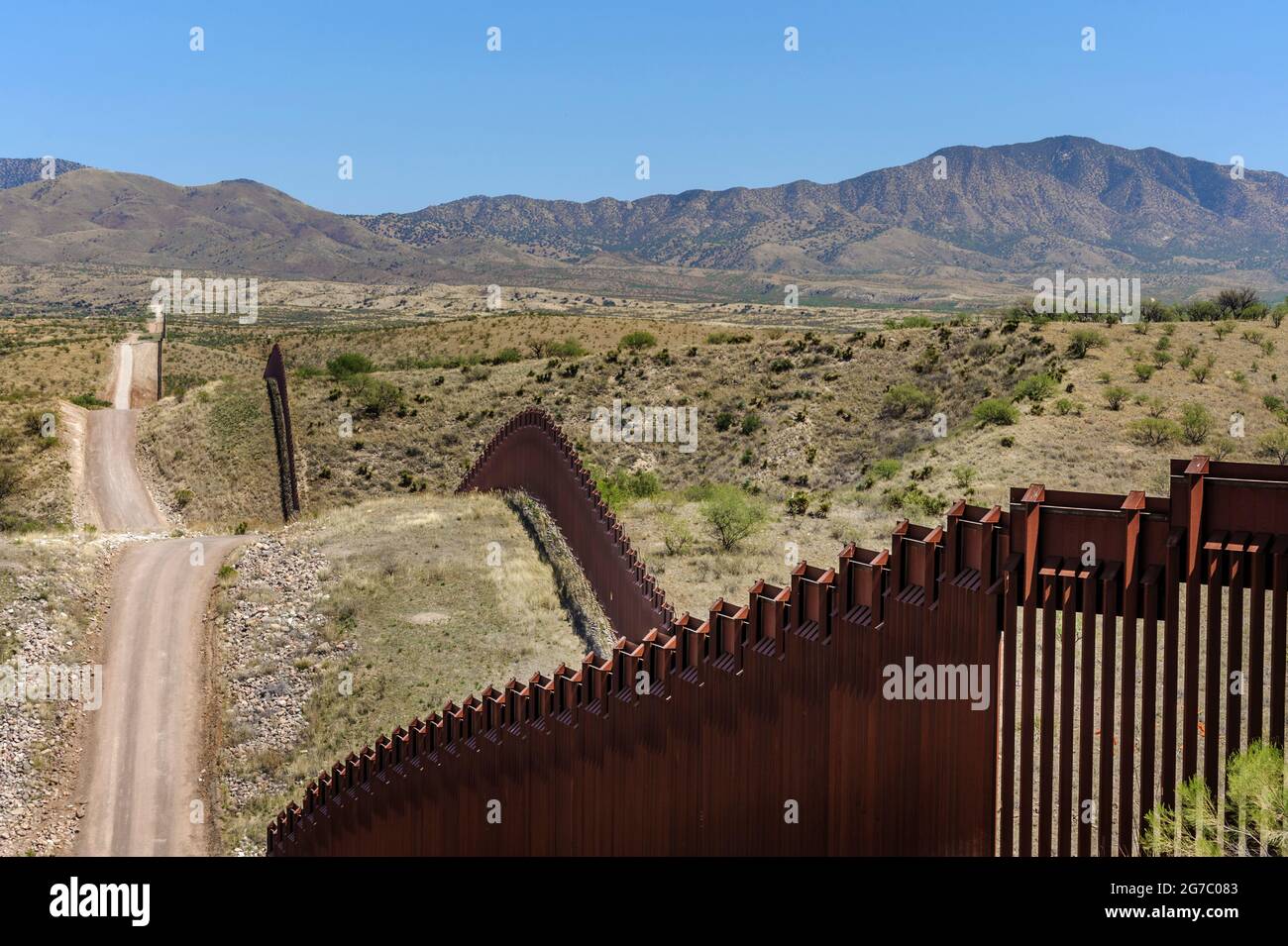 US border fence on the Mexico border, east of Nogales Arizona USA, and Nogales Sonora Mexico, viewed from US side, showing how the fence follows the t Stock Photo