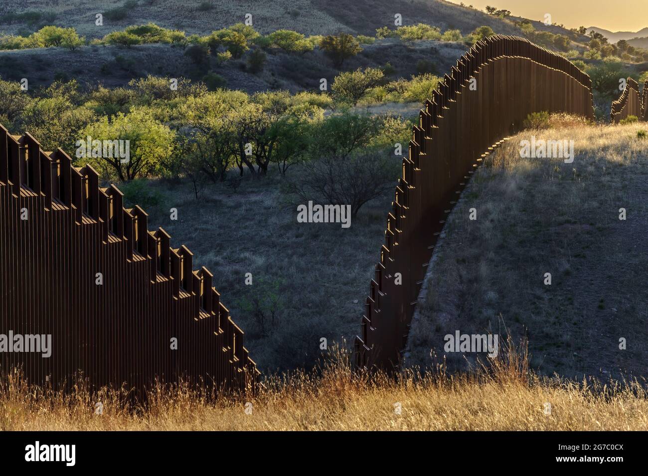 US border fence on the Mexico border, east of Nogales Arizona and Nogales Sonora Mexico, viewed from US side, looking southwest at sunset. Stock Photo