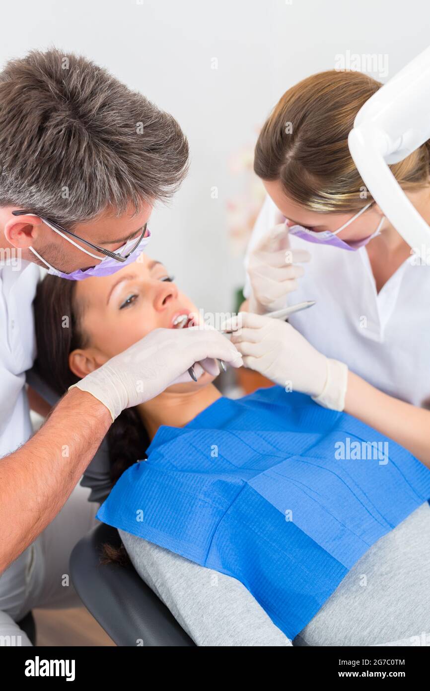 Female patient with dentist and assistant in a dental treatment, wearing masks and gloves Stock