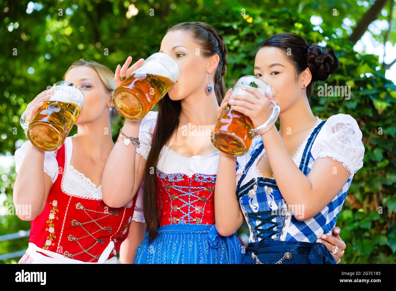 In Beer garden - female friends in Tracht, and Dirndl in Bavaria, Germany Stock Photo