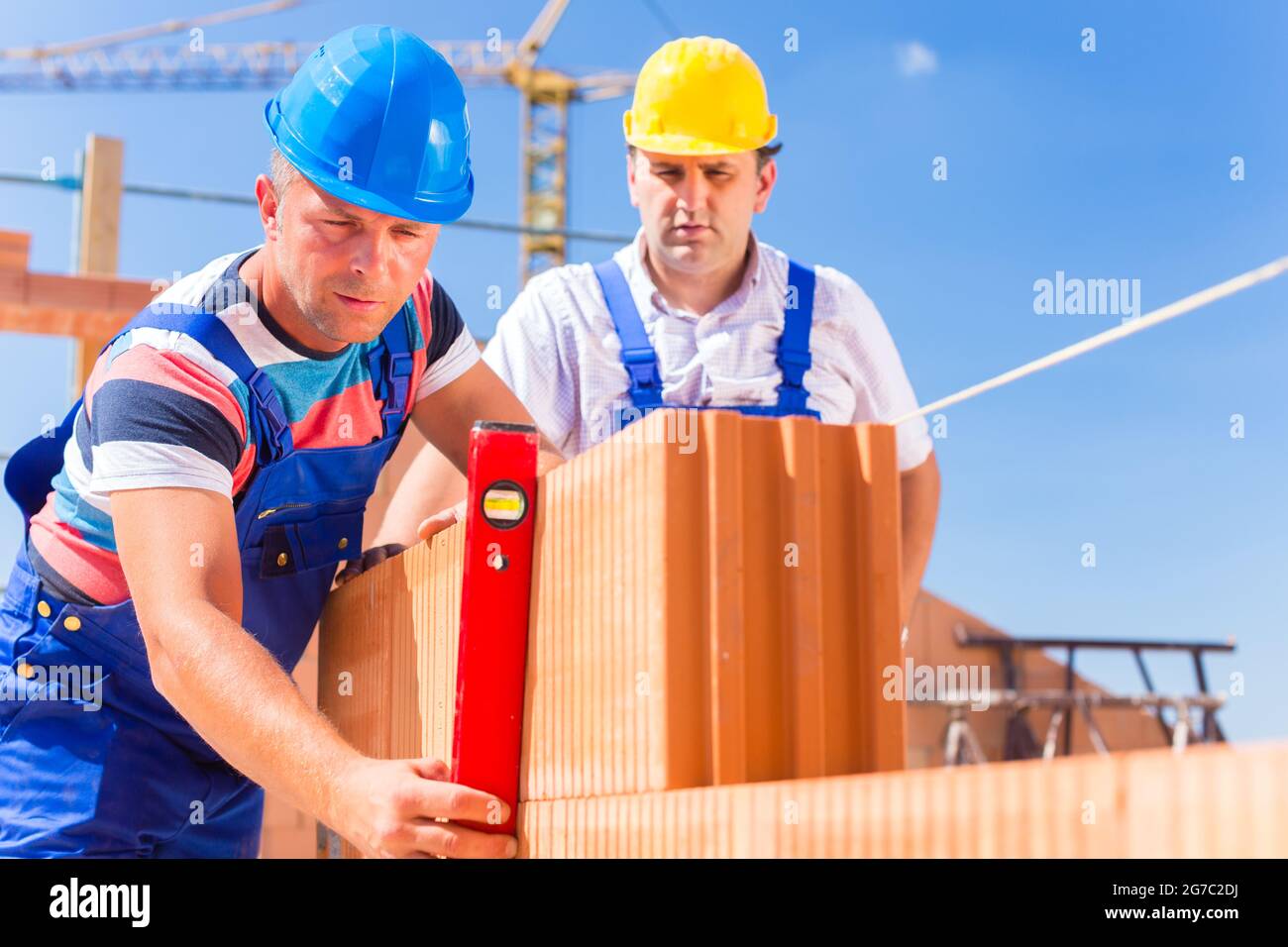 Construction site workers or bricklayer with helmets controlling