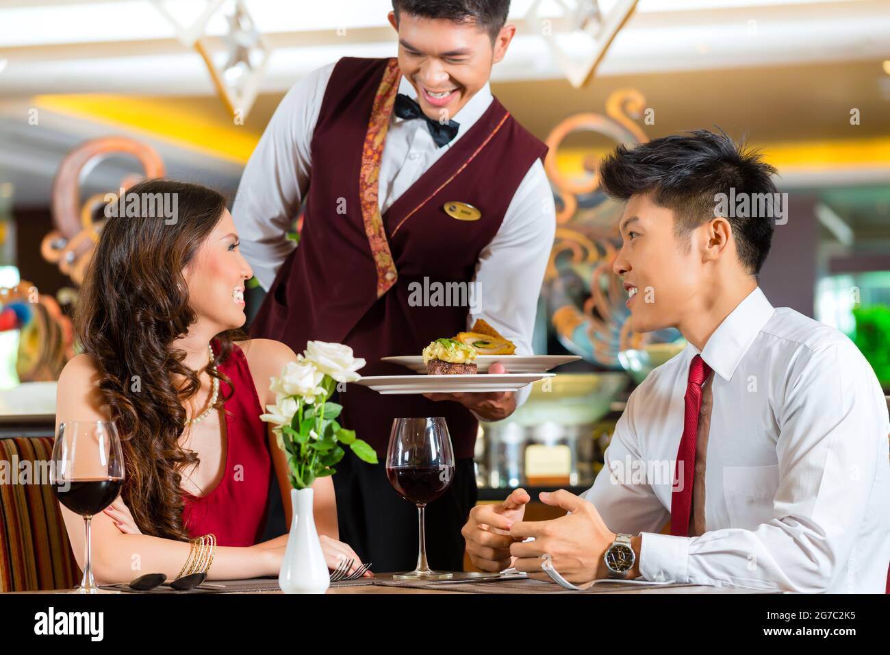 Asian Chinese couple - Man and woman - or lovers having a date or romantic  dinner in a fancy restaurant while the waiter is serving food Stock Photo -  Alamy