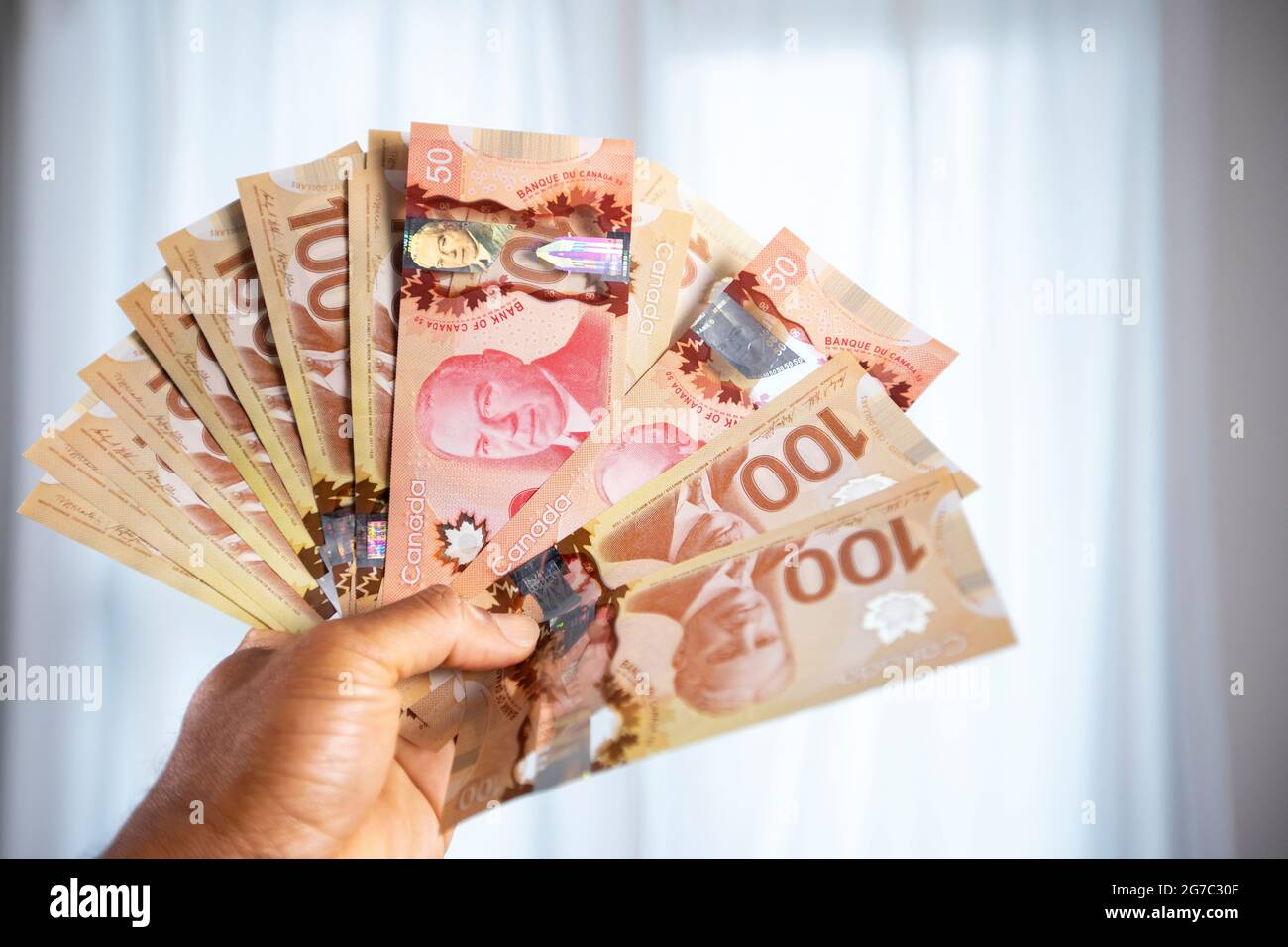 Man hand holding Canadian one hundred dollar and fifty dollar bills, paper money. Stock Photo