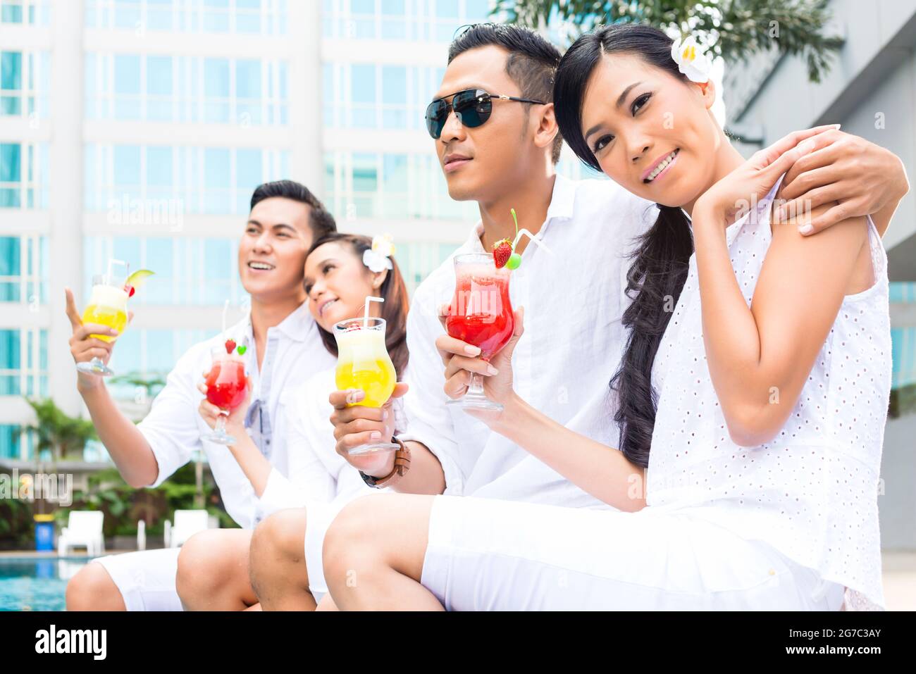 Asian couples drinking cocktails at hotel swimming pool Stock Photo