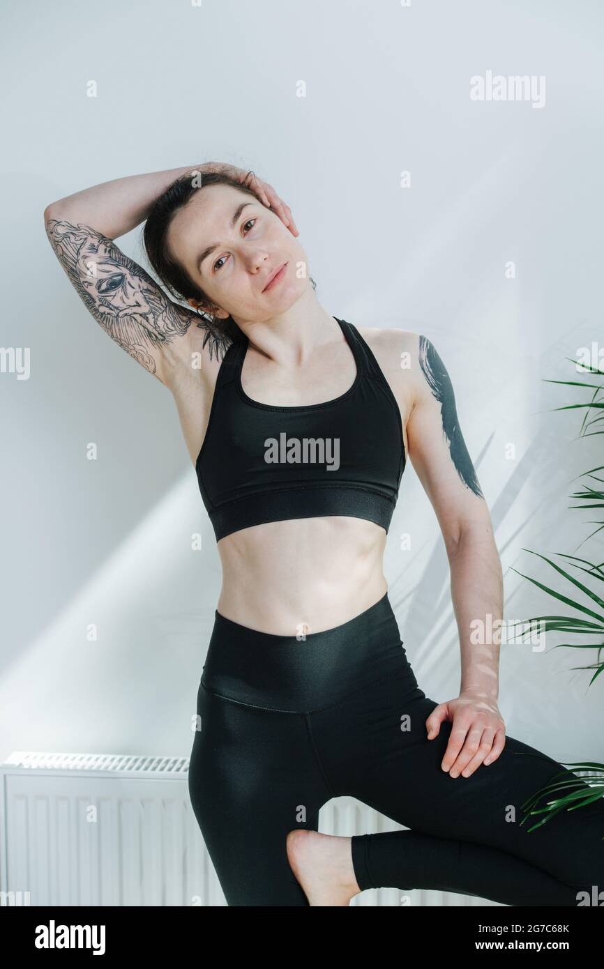 Portrait of young woman with shoulder tattoos posing in a yoga sportswear  Stock Photo - Alamy