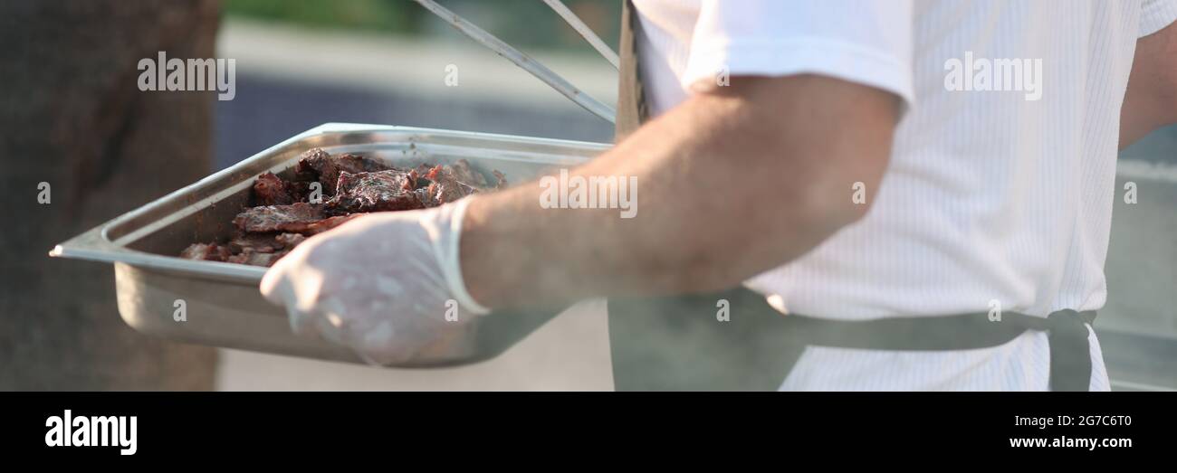 Cook carries baking sheet with grilled meat Stock Photo Alamy